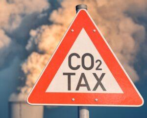 Sign reads "CO2 TAX" in front of smokestack