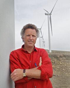David McDermott Hughes standing in front of wind turbines headshot.