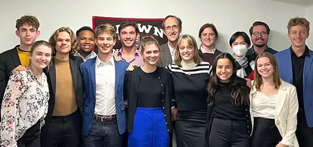 Timmons Roberts and students group photo in front of a Brown University banner.