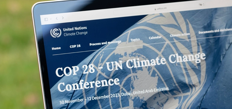 Laptop screen showing COP 28 banner with UN Flag and conference information